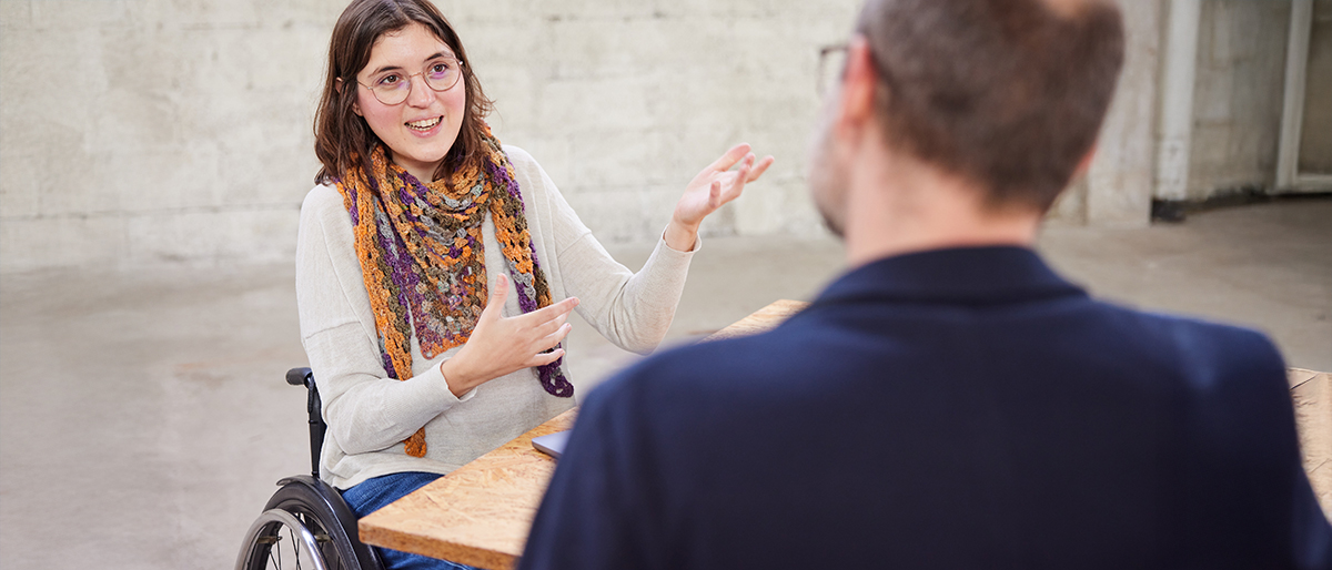 Eine Frau im Rollstuhl berät einen Klienten