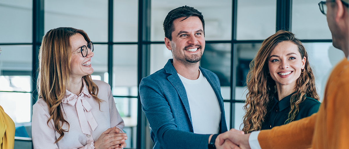 Gruppe von Inklusionsbeauftragten im Austausch, zwei begrüßen sich mit Handschlag